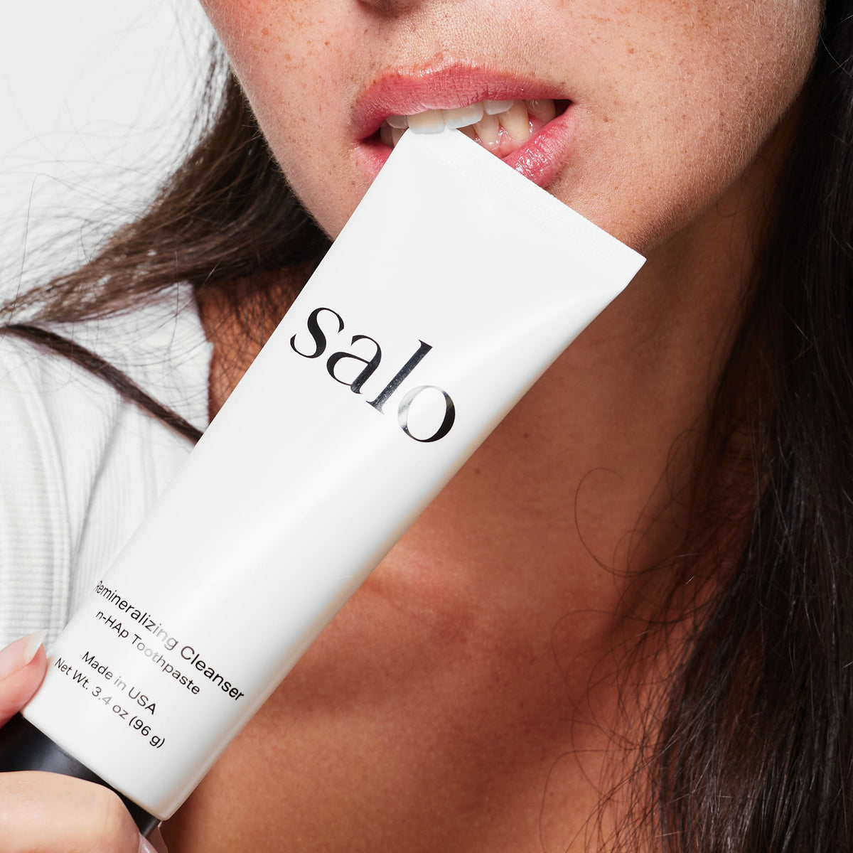 Close view of the Salo Remineralizing Cleanser held to the mouth