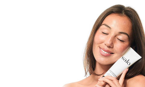 Woman with eyes closed holding the Salo Remineralizing Cleanser to her cheek
