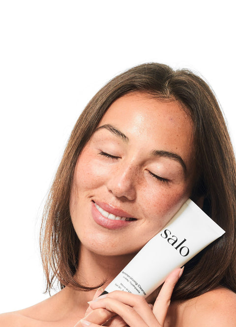 Woman with eyes closed holding the Salo Remineralizing Cleanser to her cheek